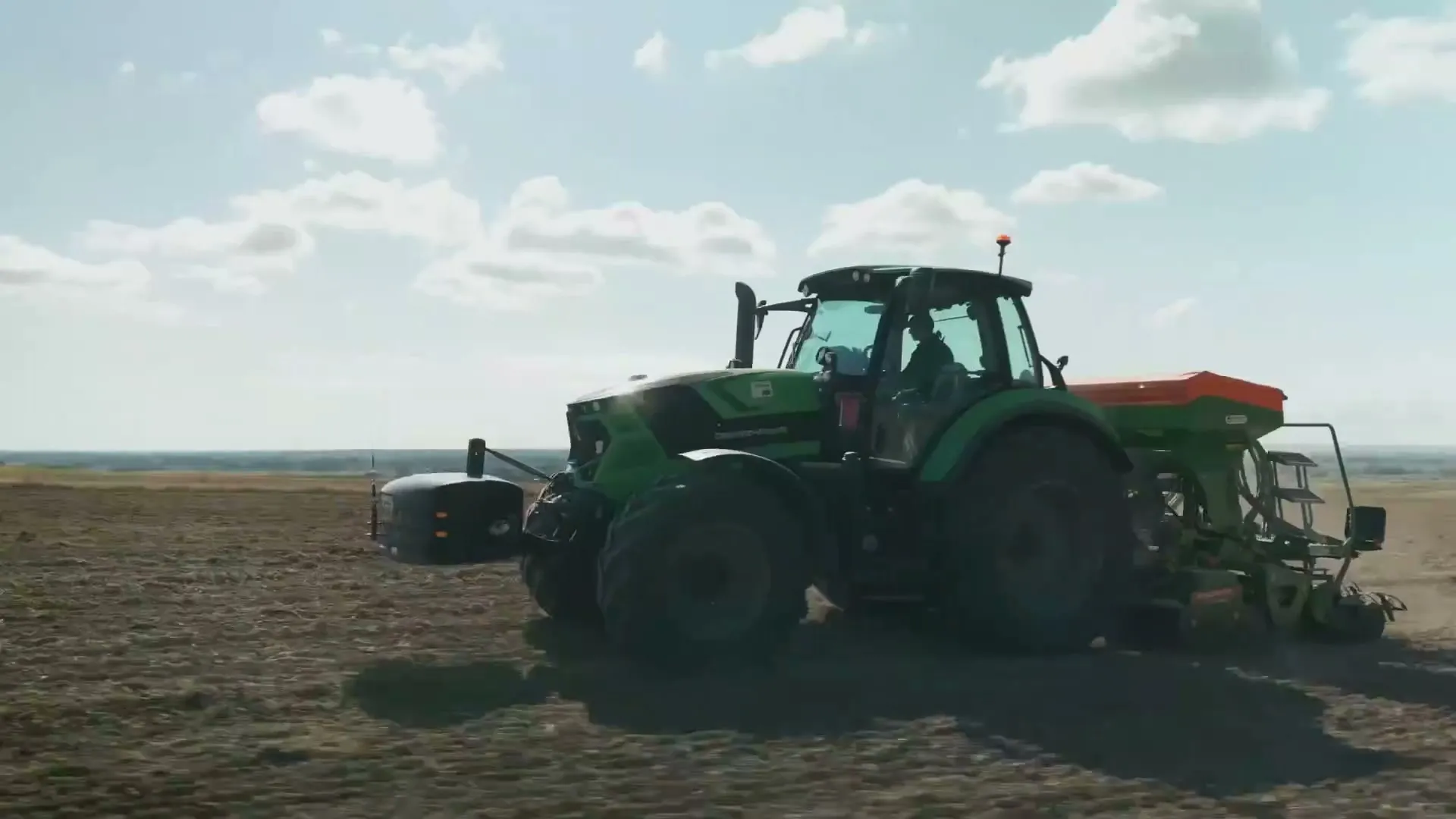 Tractor con implemento agrícola trabajando un lote extenso
